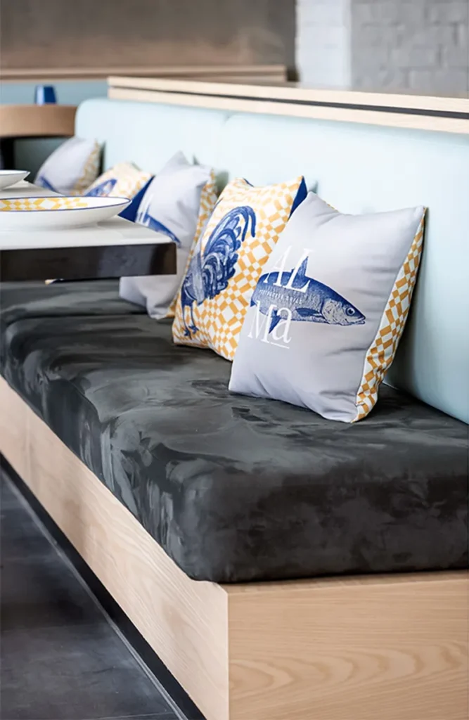 A Hong Kong restaurant's booth seating features a black cushion and decorative fish-themed pillows.