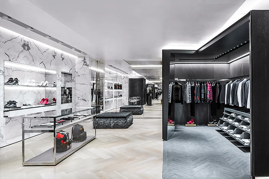 Sleek interior of a luxury store with marble walls, showcasing handbags, shoes, and menswear.