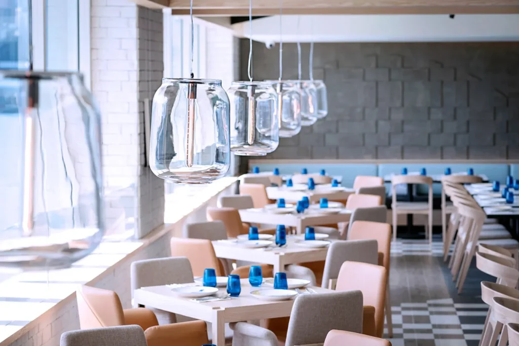 Spacious restaurant interior with pendant glass lights, modern furniture, and large windows.