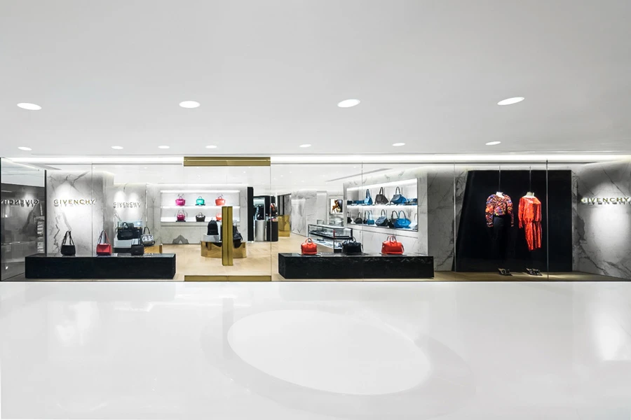 Elegant fashion boutique interior featuring marble display for vibrant handbags, sleek fixtures, and chic clothing.